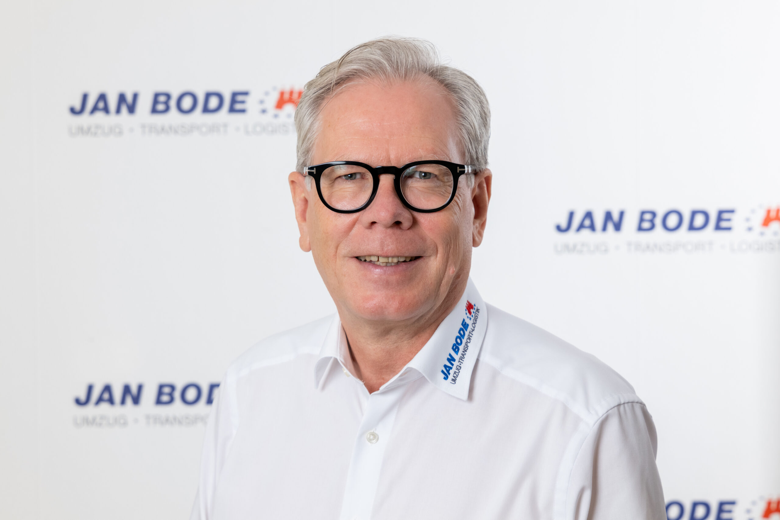 Porträtfoto des lächelnden Martin Delloch vor der "JAN BODE" Logowand