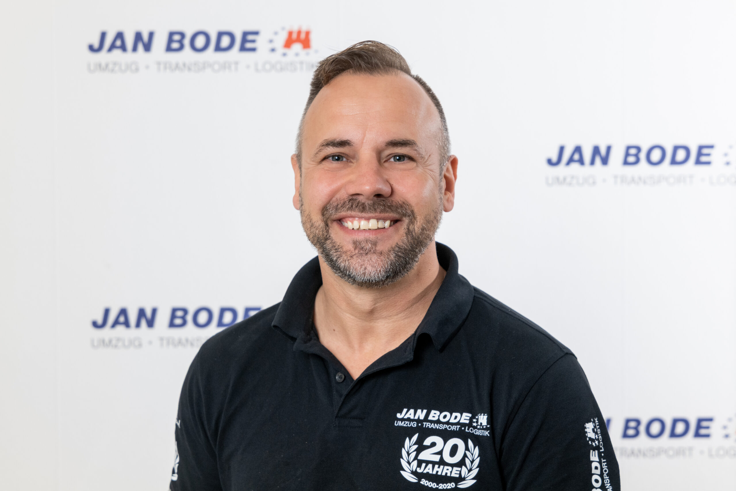 Porträtfoto des lächelnden Thomas Haltenhoff vor der "JAN BODE" Logowand
