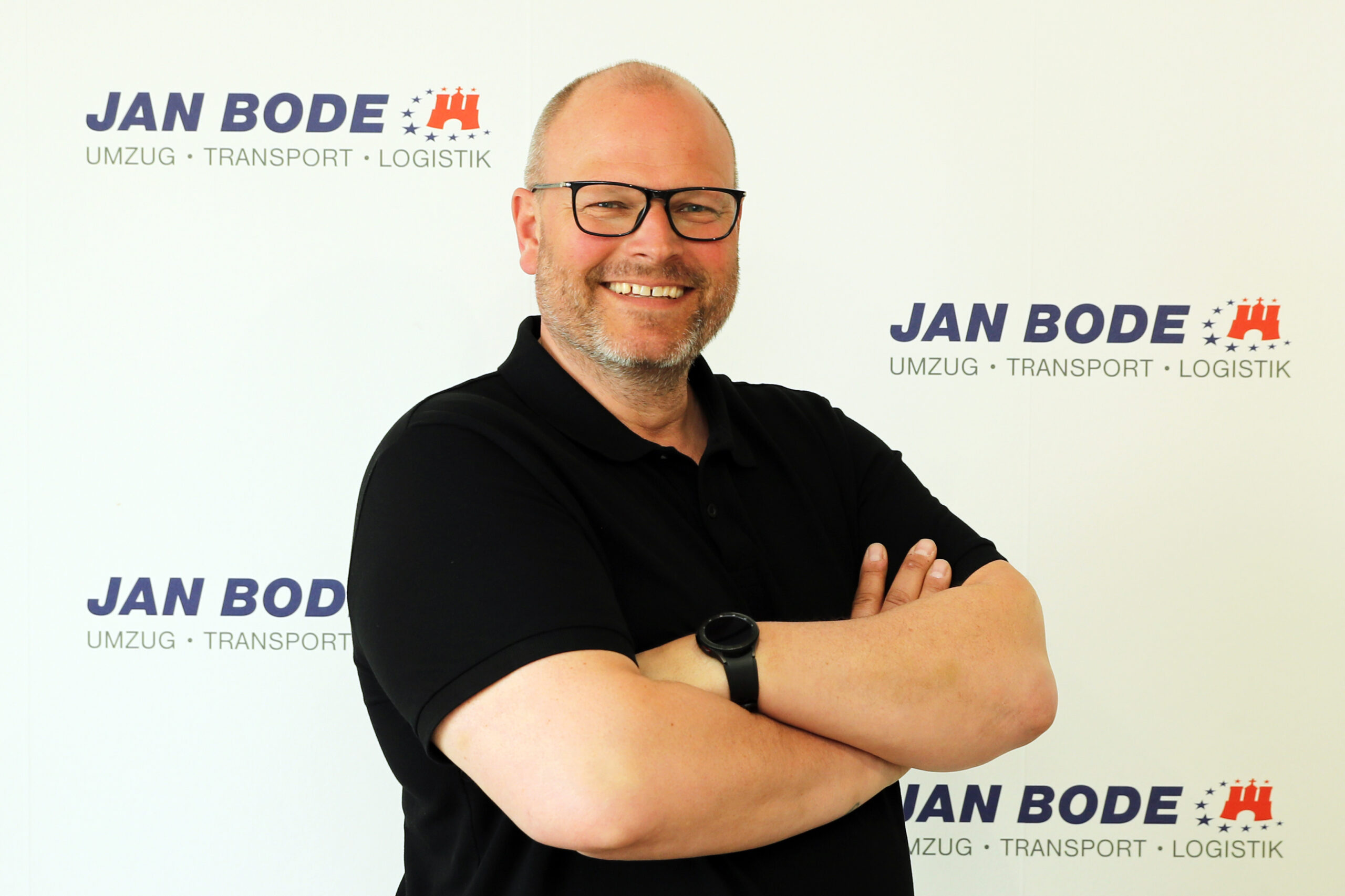 Mitarbeiter Philip Kröger lächelnd vor einer Wand mit dem Bode Logo