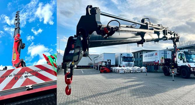 LKW-Ladekran mit Teleskopausleger steht auf dem Vorhof einer Speditionshalle